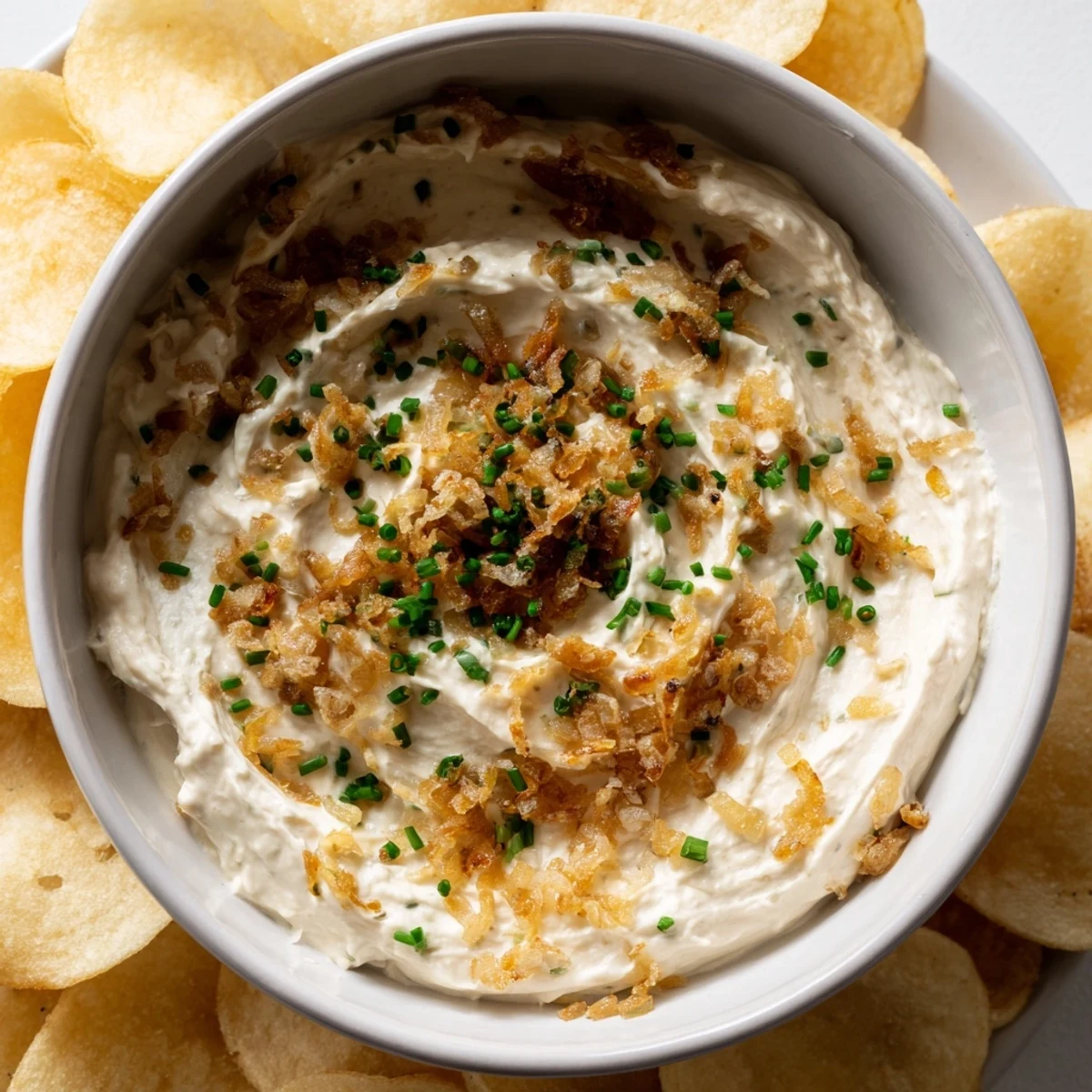Crispy, golden potato chips surround a bowl of creamy onion dip, a perfect party appetizer.