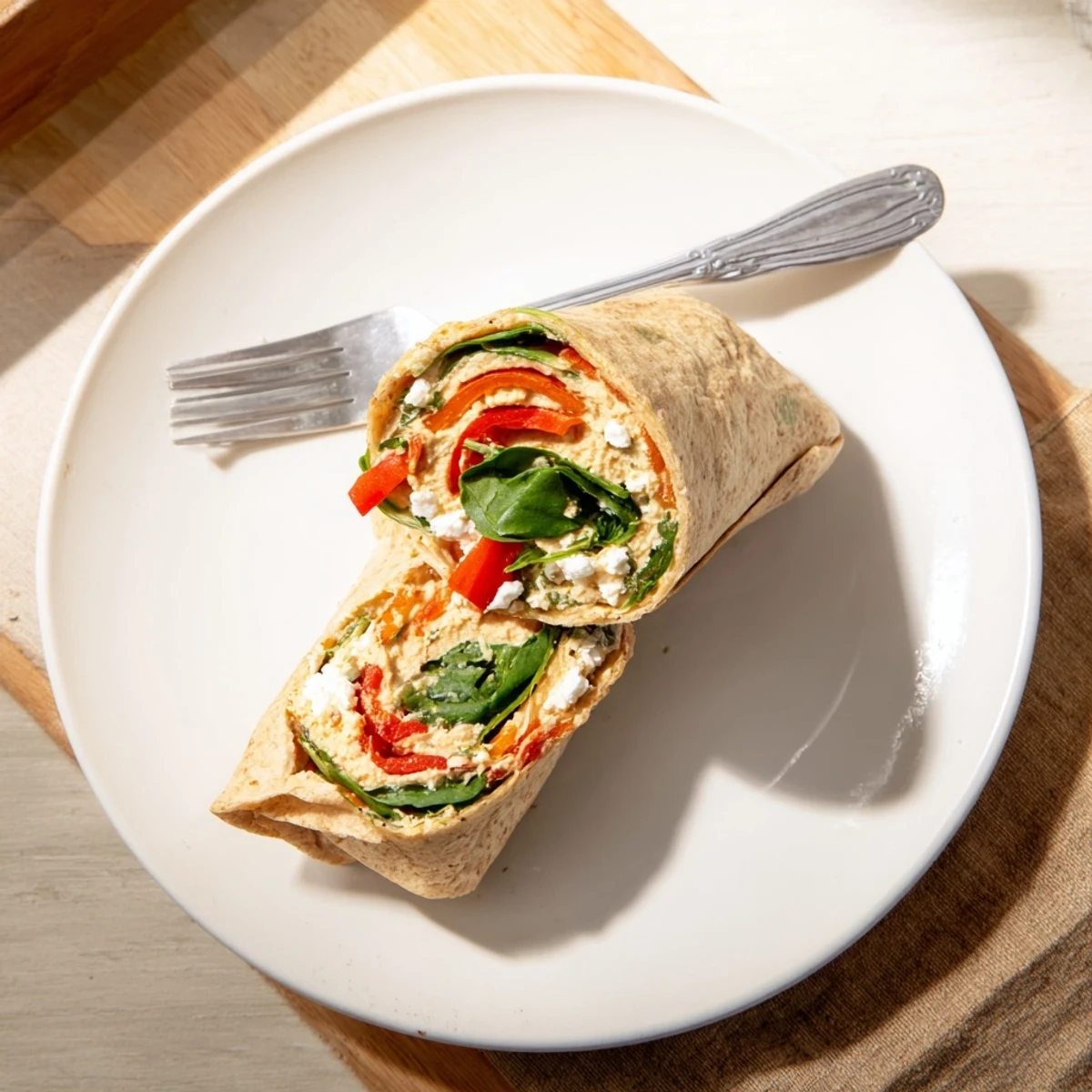 A diagonal view of a vibrant Mediterranean Veggie Wrap stuffed with spinach and crumbled feta, ready to eat.