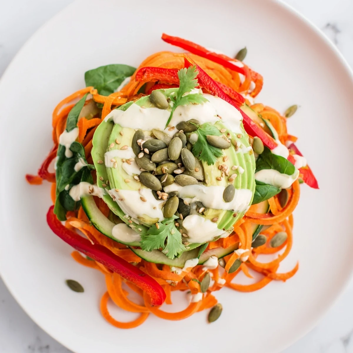 Vibrant Carrot Noodle Skincare Bowl topped with crisp veggies, creamy avocado, and a zesty tahini-lime dressing.  