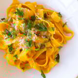 Golden roasted butternut squash pasta in a shallow bowl, topped with fresh sage and a light dusting of Parmesan cheese.