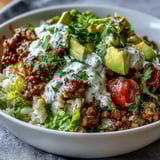 Low Carb Burrito Bowl garnished with avocado, cheddar, sour cream, and lime.