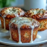 Golden muffins bursting with lemon zest and poppy seeds, drizzled with a tangy lemon glaze for a bright, refreshing flavor.