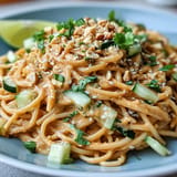 Vibrant Cold Peanut Sesame Noodles topped with crunchy peanuts and fresh herbs.