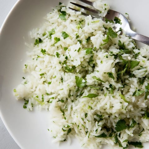 Cilantro lime rice with fluffy grains and vibrant green herbs, served warm as a side dish for tacos.