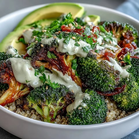 Crispy roasted broccoli and red onion over fluffy quinoa in the Roasted Broccoli Bowl, drizzled with creamy tahini sauce and topped with avocado slices.
