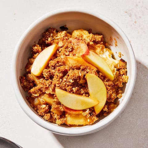 Warm Rustic Apple and Cinnamon Crumble bubbling, golden brown, best served with vanilla ice cream.