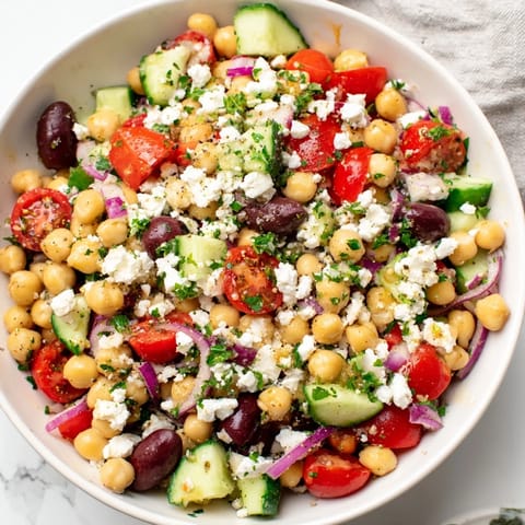 Freshly assembled Mediterranean Chickpea and Feta Bowl: chickpeas, tomatoes, olives, vegan feta, and dressing.