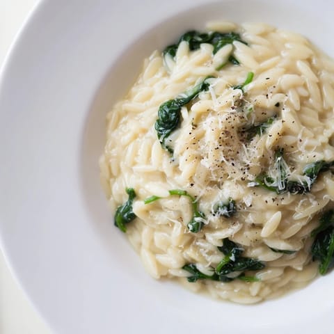A visually appealing, creamy spinach orzo boasts a rich, cheesy sauce with fresh ingredients.
