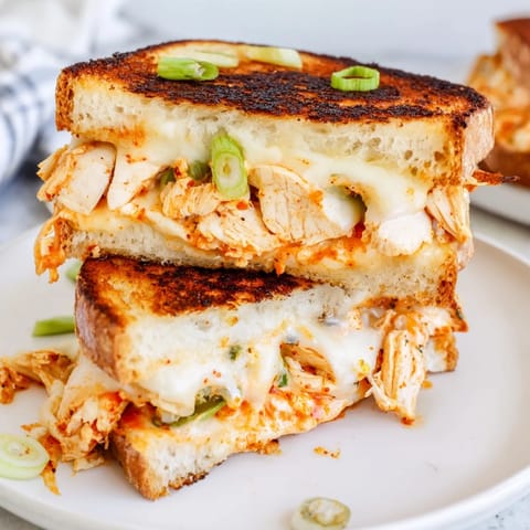 A close-up of a flavorful Gochujang Mayo Chicken Sandwich, showing off spicy chicken and gooey cheese.