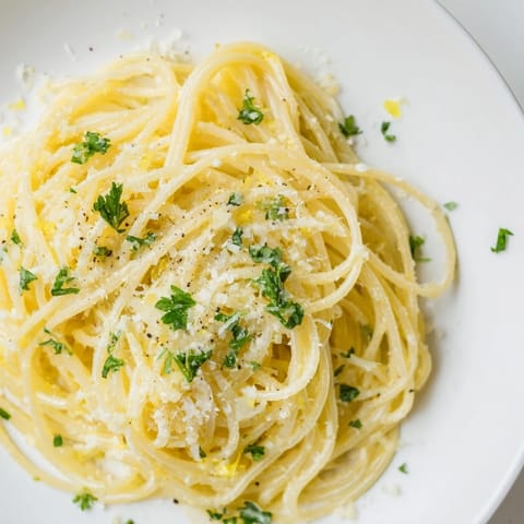 Silvery capellini noodles glistening with a golden lemon-butter sauce, topped with fresh parsley and grated Parmesan.  