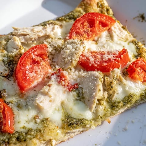 Slice of steaming hot Chicken Pesto Pizza with bubbly mozzarella and juicy tomatoes, served on a rustic wooden cutting board for a family dinner.