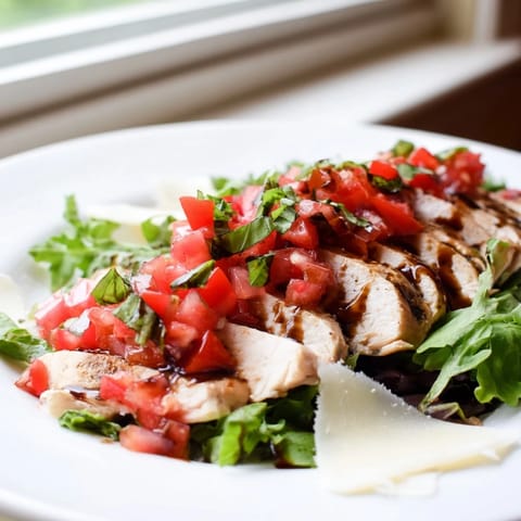 Bruschetta Chicken Salad served on a white platter with shaved Parmesan and bright lemon wedges.