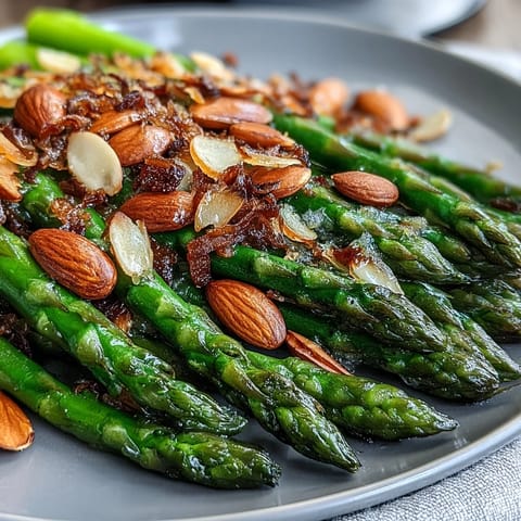 Bright asparagus spears sautéed in lemon butter and topped with golden toasted almonds for a vibrant, spring-inspired side dish.
