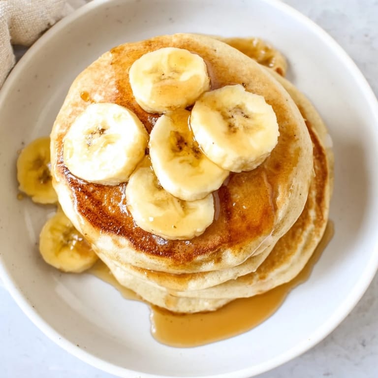 Plate piled high with Weekend Golden-Brunch Banana Pancakes, cooked perfectly and ready for a delicious brunch.