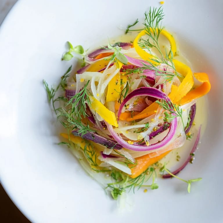 This fresh The Spinning Top salad showcases colorful, thinly sliced vegetables arranged elegantly on a plate.