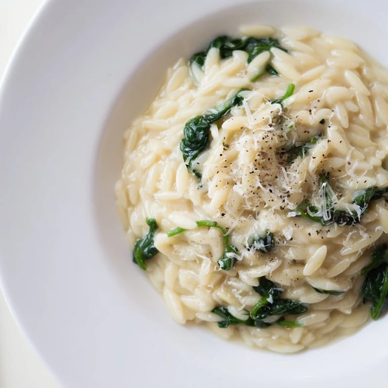 A visually appealing, creamy spinach orzo boasts a rich, cheesy sauce with fresh ingredients.