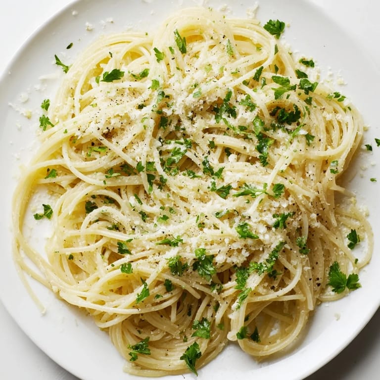 A close-up of Lemon Butter Pasta Light in a white bowl, featuring tender angel hair coated in a velvety citrus sauce.  