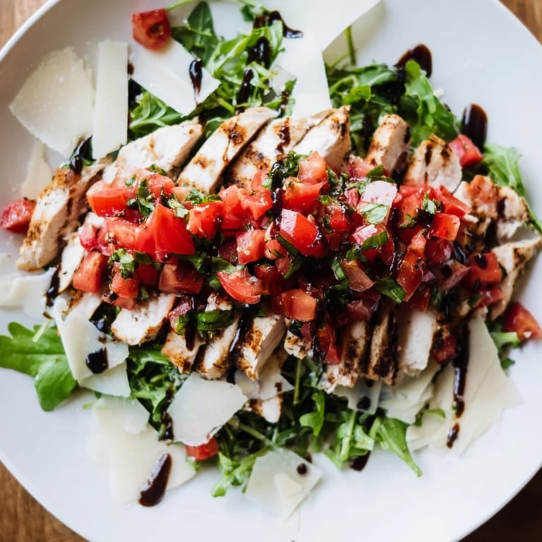 Juicy grilled chicken breast layered over a fresh green salad with a colorful tomato-basil topping.