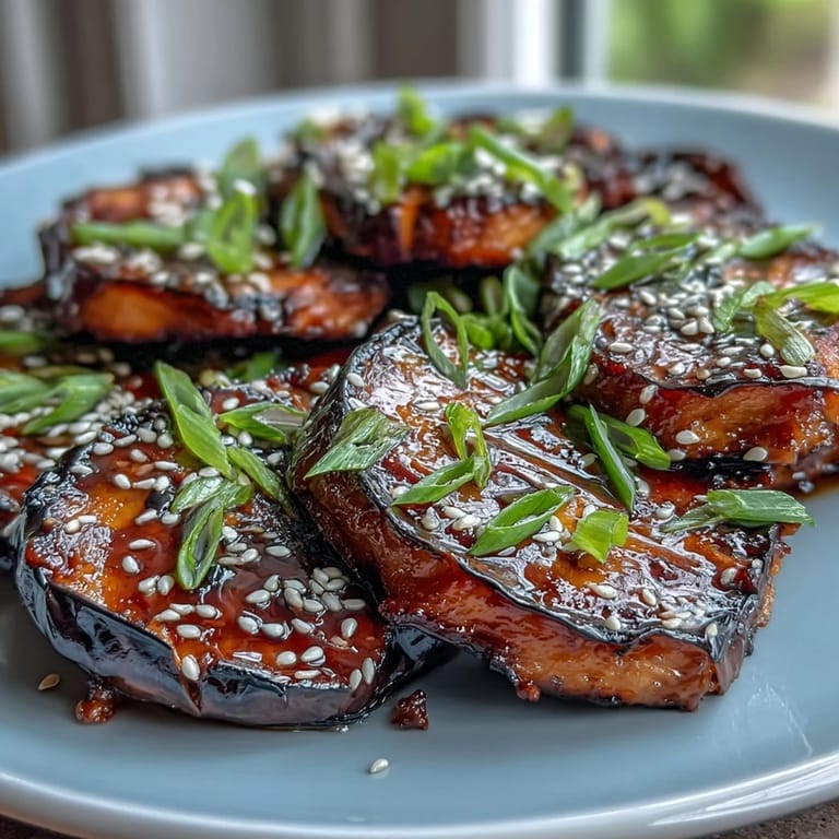 Rich and tender miso-glazed eggplant with a glossy finish, served warm and garnished with sesame seeds and green onions.