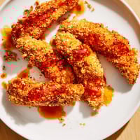 Golden-brown crispy panko chicken tenders drizzled with fiery hot honey, ready to eat and enjoy!